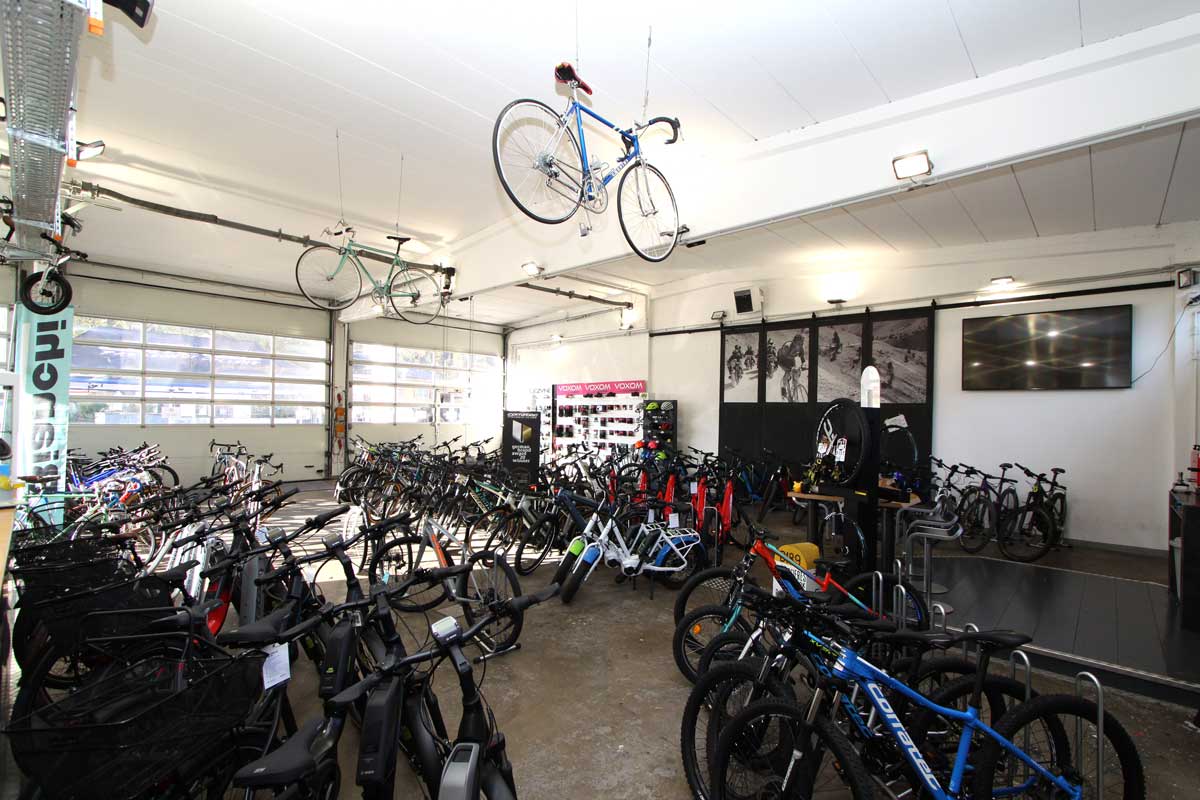 radservice oberau_Raum mit Fahrrädern und zwei an der Decke hängenden Rädern_Radsport Burda